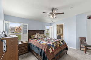 Bedroom featuring light colored carpet, baseboards, a ceiling fan, and ensuite bathroom