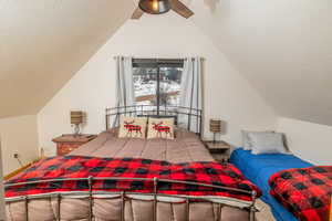 Bedroom featuring ceiling fan, vaulted ceiling, and a textured ceiling