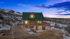 View of front facade featuring log veneer siding, metal roof, an attached garage, a mountain view, and dirt driveway