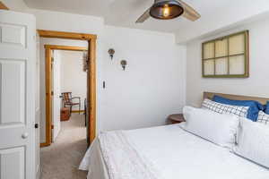 Carpeted bedroom with a ceiling fan
