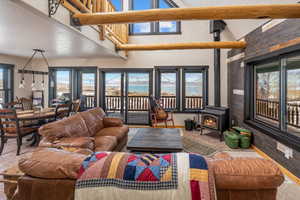 Living area featuring a textured ceiling, beamed ceiling, a wood stove, and a healthy amount of sunlight