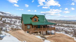 Rustic home with a porch, metal roof, a garage, and dirt driveway