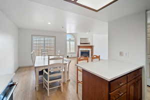 Kitchen featuring light wood-style flooring, a tile fireplace, recessed lighting, light countertops, and a breakfast bar area