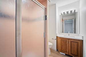 Bathroom with wood finished floors, vanity, a shower stall, and toilet