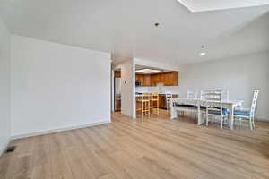 Dining room with light wood-style flooring, visible vents, and baseboards
