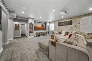 Home Theater room with included screen & projector, faux brick accent wall, barn door and newer carpet.