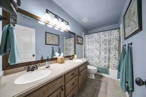 One of two full bathrooms upstairs featuring a dual vanity , solid surface countertops and tile flooring.