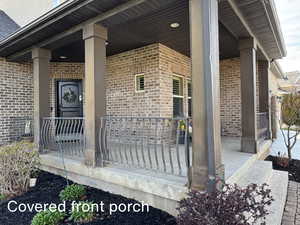 Entrance to property featuring a porch and brick siding