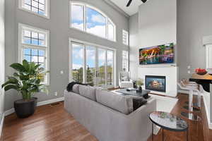 Living area with a wealth of natural light, baseboards, a glass covered fireplace, and hardwood / wood-style flooring