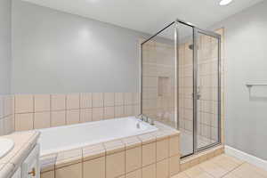 Full bathroom with a bath, tile patterned floors, a stall shower, and vanity