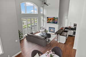 Living room with a ceiling fan, dark wood finished floors, baseboards, and a glass covered fireplace