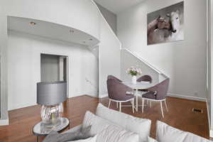 Living room with visible vents, baseboards, stairway, and wood finished floors