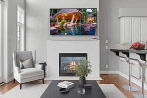 Living room with baseboards, a glass covered fireplace, and wood finished floors