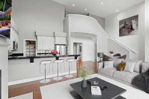 Living area featuring wood finished floors, recessed lighting, a high ceiling, and stairs