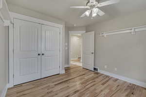 Bedroom featuring a closet, light wood-type flooring, baseboards, and ceiling fan