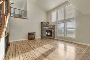 Living room with, a beautiful stone fireplace, stairway, wood-type flooring, and high vaulted ceiling
