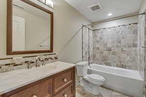 Full bath with bathing tub / shower combination, vanity, toilet, and decorative backsplash