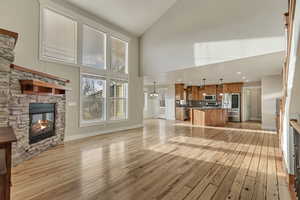 Living room with a stone fireplace, baseboards, recessed lighting, and high vaulted ceiling