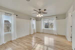Room featuring hardwood / wood-style flooring, a ceiling fan, and a wainscoted wall