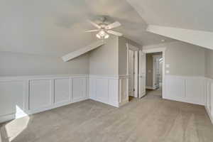 Additional living space with a ceiling fan, light carpet, and lofted ceiling