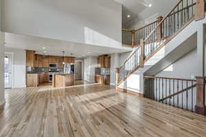 Living room, recessed lighting, a high ceiling, and light wood floors