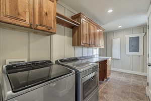Washroom featuring a decorative wall, separate washer and dryer, and cabinet space