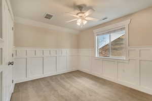 Bedroom featuring a decorative wall,  light colored carpet, and a ceiling fan