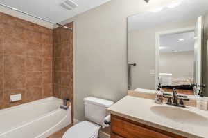 Ensuite bathroom featuring visible vents, toilet, tub / shower combination, vanity, and tile patterned floors