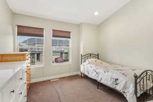 Carpeted bedroom with visible vents, baseboards, multiple windows, and recessed lighting