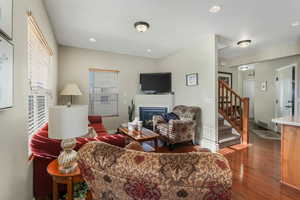 Living area featuring a glass covered fireplace, recessed lighting, stairway, wood finished floors, and baseboards