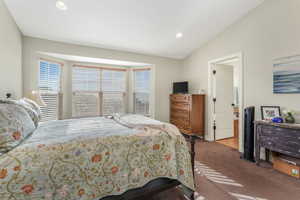 Carpeted bedroom with lofted ceiling and recessed lighting