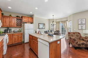 Kitchen featuring a sink, light countertops, white appliances, and dark wood finished floors