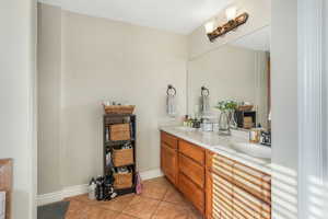 Bathroom with a sink, tile patterned floors, double vanity, and baseboards