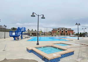 Community pool featuring fence, a patio, a community hot tub, and a water slide