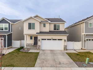 View of front of house with a gate, stone siding, stucco siding, fence, and an attached garage