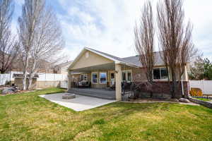 Back of house with a fire pit, a patio area, brick siding, a fenced backyard, and a lawn