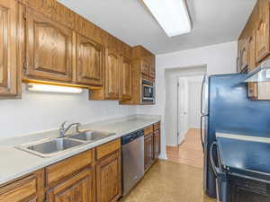Kitchen with light countertops, brown cabinets, appliances with stainless steel finishes, and a sink