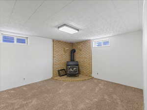 Below grade area featuring a wood stove and carpet