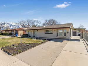 Ranch-style house featuring concrete driveway, a mountain view, a front lawn, brick siding, and fence