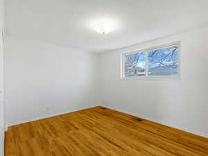 Spare room featuring light wood-type flooring, baseboards, visible vents, and a textured ceiling