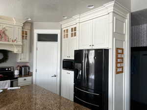 Kitchen featuring glass insert cabinets, white cabinets, appliances with stainless steel finishes, and premium range hood