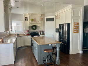 Kitchen featuring a sink, a center island, light stone countertops, and stainless steel appliances