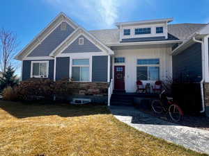 View of front facade featuring a front yard and a shingled roof