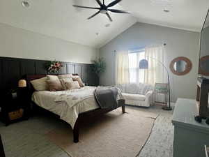 Bedroom featuring a ceiling fan, light carpet, vaulted ceiling, and a textured ceiling