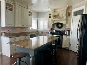 Kitchen with a kitchen bar, dark wood-type flooring, a sink, and black appliances