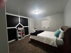 Bedroom featuring a textured ceiling, visible vents, and carpet floors