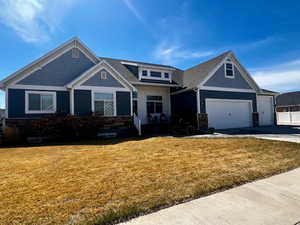 Craftsman-style house featuring a garage, concrete driveway, and a front lawn