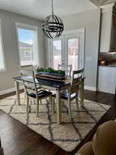 Dining area with dark wood-type flooring, baseboards, an inviting chandelier, and a textured ceiling