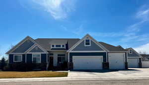 Craftsman-style house featuring a garage, a front yard, driveway, and stone siding