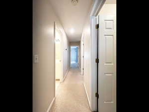 Corridor featuring light carpet and baseboards